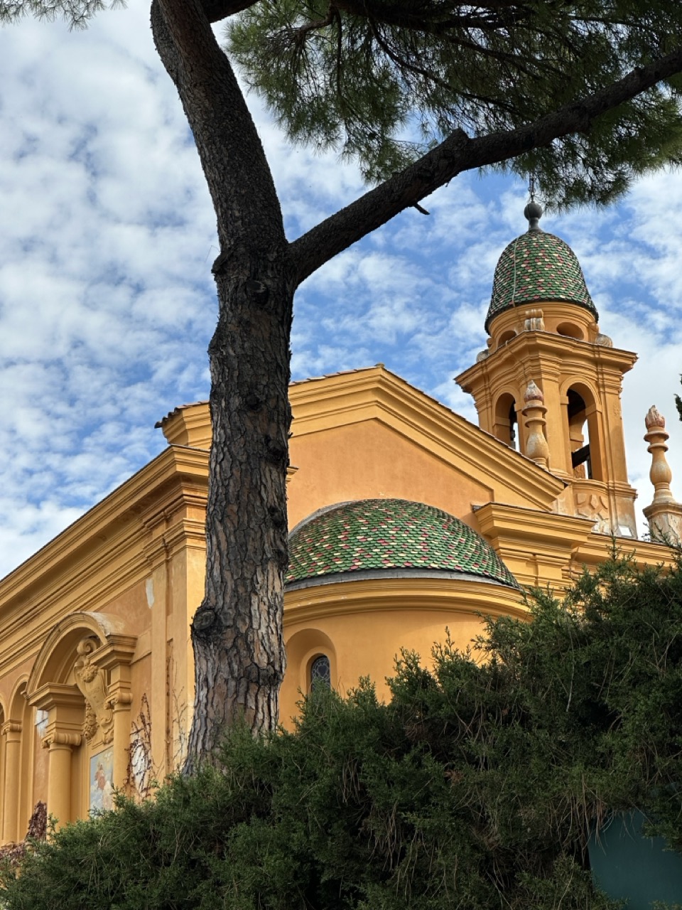 An orange church seen through pine trees